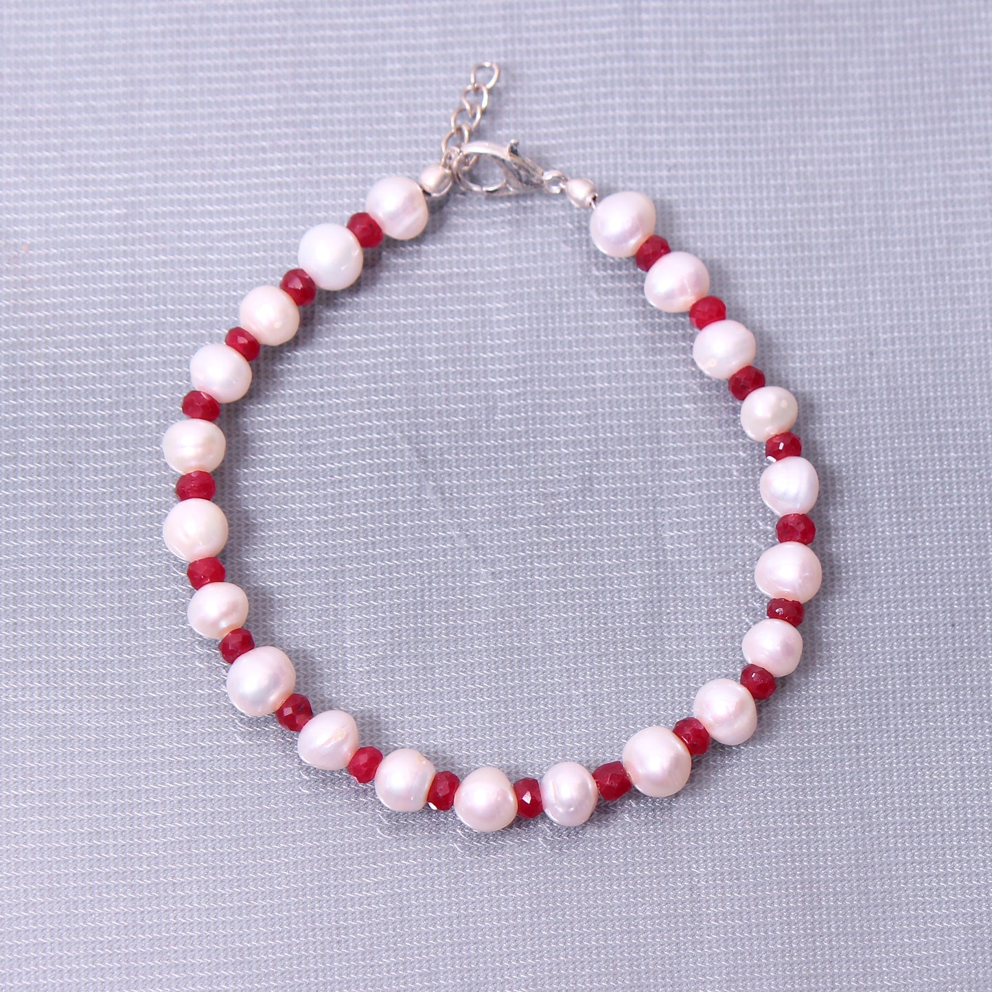 beaded bracelet with ruby and pearls gray background