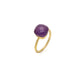Gold plated engagement ring with faceted purple gemstone on white background